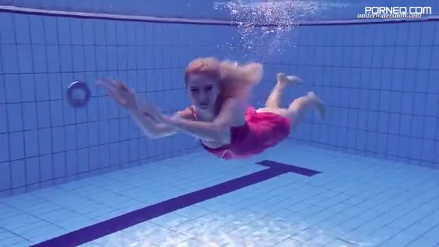 Playful blonde girl swims naked in Olympic swimming pool